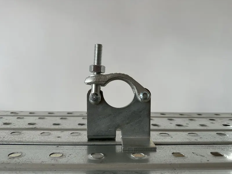 Scaffold board retaining coupler with a flat plate and lip below the tube clamp